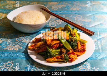 Chinesisches Huhn im Hunan-Stil mit gemischtem sautiertem Gemüse und weißem Reis Stockfoto