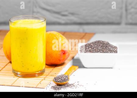 Stillleben mit Frucht-Smoothie, Pfirsich- und Chiasamen auf weißem Backstein-Hintergrund, vertikaler Auflösung, gesunder Sommerdiät, Copy Space Stockfoto