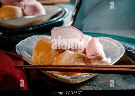 Traditionelles japanisches Erdbeer- und Mango-Mochi-Eis auf einem Marmorküchentisch mit romantischer, dramatischer Beleuchtung Stockfoto