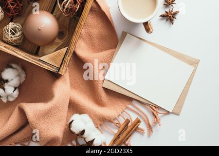 Herbstlicher gemütlicher Schreibtisch mit romantischem Brief, Schal, Kaffeetasse, Baumwolle, Kerze und Dekorationen auf Weiß. Flach liegend, Draufsicht Stockfoto