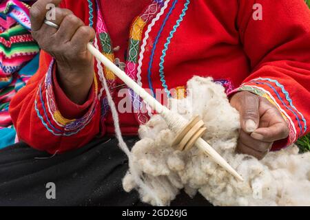 Quechua Frau mit Alpakawolle und Werkzeug, um es in Garn zu spinnen; El Parador de Moray, Sacred Valley, Peru. Stockfoto
