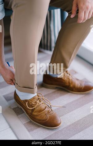 Bräutigam zieht braune Brogues auf seine Beine. Nahaufnahme Stockfoto