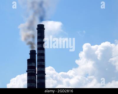 Rauchende Kamine vor dem Hintergrund eines klaren Himmels und weißer Wolken, kopieren Raum Stockfoto