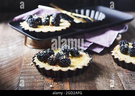 Frisch gebackene Brombeeren- und Vanillepudding-Torten. Stockfoto