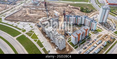 Luftaufnahme von oben des im Bau befindlichen Stadtgebiets mit Wohngebäuden und funktionierenden Turmdrehkranen. Panorama-Luftaufnahme. Stockfoto