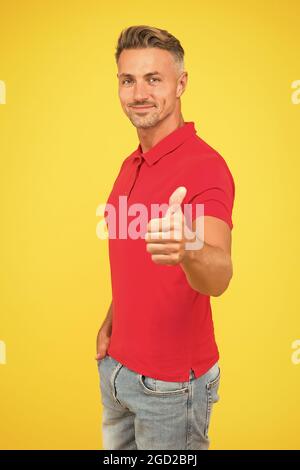 Sei dein Bestes. Glücklicher Kerl geben Daumen nach oben gelben Hintergrund. Geste zur Genehmigung. Handzeichen. Lässige Mode. Modischer Style. Modische Herrenmode. Herrenbekleidung. It Stockfoto