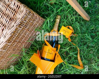 Veuve Clicquot Luxus-Champagner-Flasche & Präsentationsbox mit Band, Picknickkorb im Freien bei grünen Outdoor-Gelegenheiten Stockfoto