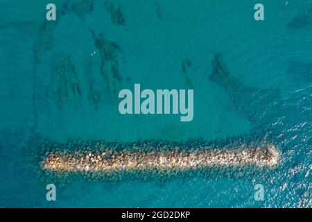 Luftaufnahme von einer fliegenden Drohne aus blauem Meerwasser und Wellenbrecher. Stockfoto