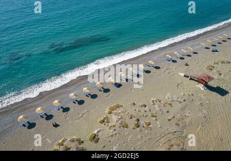 Luftaufnahme von Sonnenschirmen in einer Reihe und Rettungsschwimmerstation an einem leeren Strand. Paphos Zypern Stockfoto