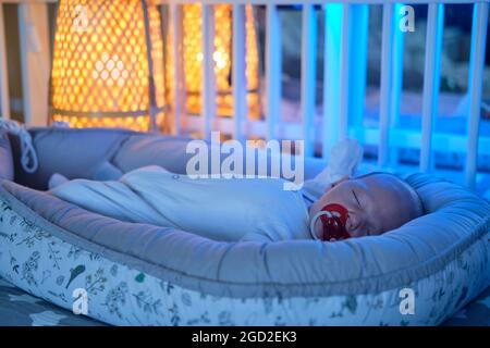 Porträt eines Jungen im Alter von einem Monat, der in einer Krippe schläft. Kaukasisches Kind im Kinderzimmer Stockfoto