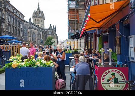 Royal Mile, Edinburgh, Schottland, Großbritannien. Agust 2021. An diesem sonnigen ersten Montag des Fringe Festivals, das den Künstlern ein größeres Publikum als am Wochenende bescherte, kehren die Massen in die High Street zurück. Im Bild: Gordon's Trattoria ist mit Kunden auf den Sitzbereichen im Freien beschäftigt. Quelle: Arch White/Alamy Live News Stockfoto