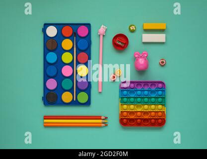 Zurück zum Schulkonzept. Farben, Bleistifte und ein Anti-Stress-Spielzeug. Blick von oben. Flach liegend Stockfoto