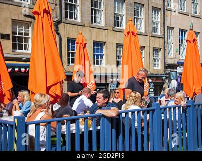 Royal Mile, Edinburgh, Schottland, Großbritannien. Agust 2021. An diesem sonnigen ersten Montag des Fringe Festivals, das den Künstlern ein größeres Publikum als am Wochenende bescherte, kehren die Massen in die High Street zurück. Im Bild: Gordon's Trattoria ist mit Kunden auf den Außensitzbereichen beschäftigt, Gordon bedient Kunden. Quelle: Arch White/Alamy Live News Stockfoto