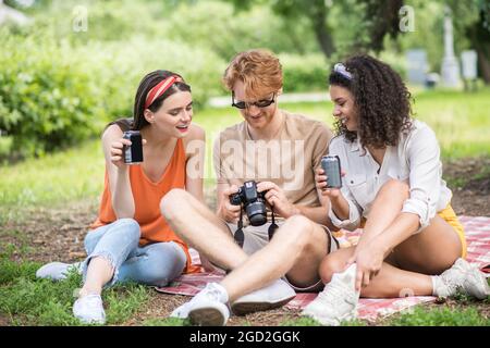 Kerl mit Kamera und Freundinnen mit Getränken Stockfoto