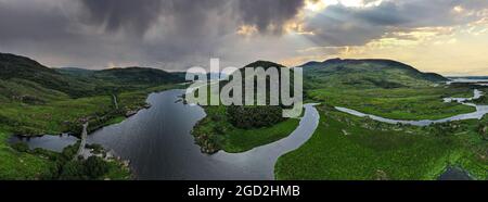 Die Sonne scheint in der Ferne durch die Wolken mit dem Owengarriff River im Killarney National Park in der Grafschaft Kerry Ireland im Vordergrund Stockfoto