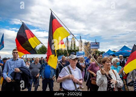 Schwerin, Deutschland. August 2021. AfD-Anhänger stehen mit deutschen Fahnen vor dem Schloss Schwerin zu Beginn der Wahlkampftour der AfD. Die Partei kämpft mit dem Slogan "Deutschland. Aber normal.“ in den Wahlkampf. Quelle: Jens Büttner/dpa-Zentralbild/dpa/Alamy Live News Stockfoto