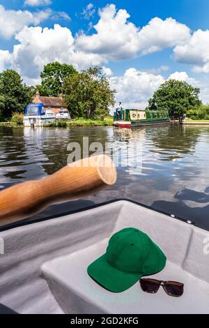 River Wey Papercourt Schleuse an einem Sommertag mit traditionellem Schmalboot-Kahn, das Schleuse einfährt, mit Ruderboot, Mütze, Sonnenbrille und Ruder im Vordergrund. Surrey UK Stockfoto