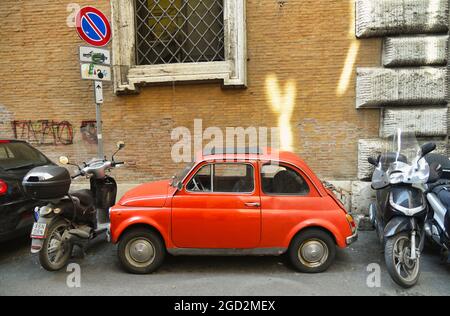 Seitenansicht eines alten roten Fiat 500, der in einer engen Straße in Rom, Italien, geparkt ist Stockfoto