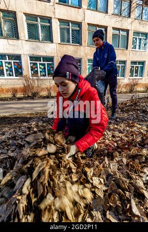 Omsk, Russland. 24. April 2021. Schülerinnen und Schüler legten Laub mit ihren Händen in eine Plastiktüte. Traditionelle russische Veranstaltungen für die Vorbereitung o Stockfoto