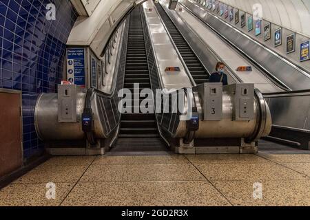 London, Großbritannien. August 2021. UV-Lichtgeräte an Rolltreppen der Londoner U-Bahn sind Teil des antiviralen Reinigungsregimes von TfL (Transport for London).an einigen Rolltreppen in ihrem Netzwerk wurden Desinfektionsgeräte installiert, die das bestehende umfassende antivirale Reinigungsverfahren von TfL ergänzen sollen. Sie sind mit dem Handlauf der Rolltreppe verbunden und nutzen ihre Bewegung zur Stromversorgung einer UV-Lampe, die Verunreinigungen abbaut und die Oberfläche kontinuierlich desinfiziert. Kredit: SOPA Images Limited/Alamy Live Nachrichten Stockfoto