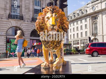 London, Großbritannien. August 2021. Löwenskulptur des Rolling Stones-Gitarristen Ronnie Wood im Piccadilly Circus, Teil des Lion Trail der Naturschutzorganisation Tusk. Auf den Straßen Londons werden lebensgroße Löwen-Skulpturen ausgestellt, die von berühmten Künstlern, Musikern und Komikern entworfen wurden, um die Gefahren von Löwen zu erkennen und Mittel für den Schutz und die Lebensgrundlagen zu beschaffen, die von COVID-19 in Afrika betroffen sind. Kredit: SOPA Images Limited/Alamy Live Nachrichten Stockfoto