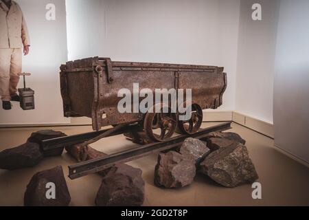 In einem Museum steht ein rostiger alter Bergbauwagen auf Schienen Stockfoto