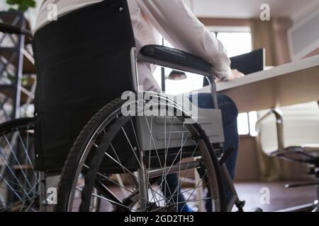 Nahaufnahme auf der Rückseite eines Rollstuhls und ein Geschäftsmann, der darin sitzt Stockfoto