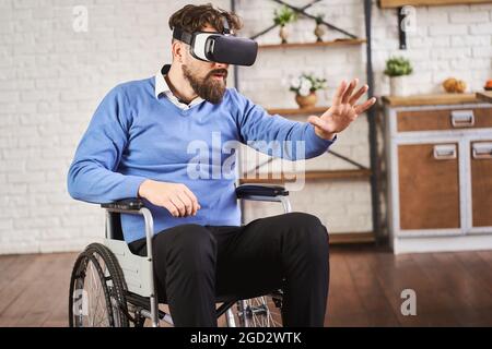 Mann, der in einem Rollstuhl sitzt und ein VR-Headset trägt Stockfoto