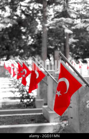 Grabsteine türkischer Soldaten KIA (Killed in Action) mit roten türkischen Flaggen auf dem Luftwaffenmärtyrertum Monochrom mit rotem Filter Eskisehir/Türkei Stockfoto