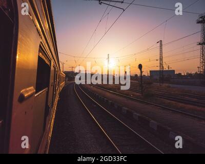 Alter Zug, der an einem klaren Sommertag den Sonnenaufgang oder Sonnenuntergang vom Passagierfenster aus einschaltet Stockfoto