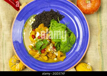 Draufsicht auf ein blaues Plättchen mit Mangohühnchen und schwarzen Linsen Stockfoto