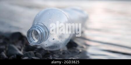 Umweltproblem. Banner Meeresverschmutzung Müll Wasser Müll Strand. Leere Flasche Plastikmüll auf Ufer Meerwasserabfall liegen. Entsorgte Flasche Stockfoto