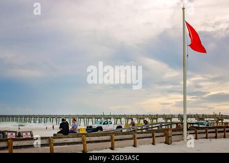 Am Pensacola Beach sitzen Menschen, während eine rote Flagge vor der Ankunft des Unwehens Michael am 9. Oktober 2018 in Pensacola, Florida, weht. Stockfoto