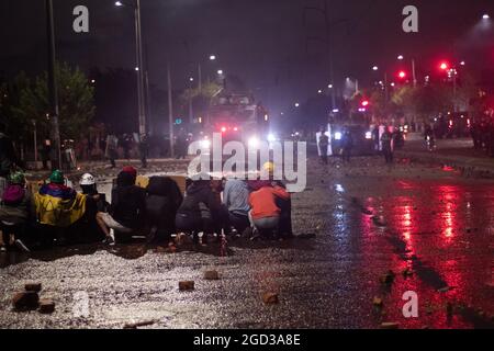 Bogota, Kolumbien, 09/08/2021, Demonstranten, die Schilde aus Holz und Metall verwendeten, um Wasser- und Tränengasbehälter zu bedecken, die von einem bewaffneten Lastwagen der kolumbianischen Bereitschaftspolizei während der Anti-Regierung geschossen wurden, was zu Zusammenstößen zwischen Demonstranten und der kolumbianischen Bereitschaftspolizei (ESMAD) inmitten der Räumung von Demonstranten führte, die während der letzten 3 in den Tibabuyes lagerten Monatelange regierungsfeindliche Proteste im Norden Bogotas, Kolumbien Stockfoto