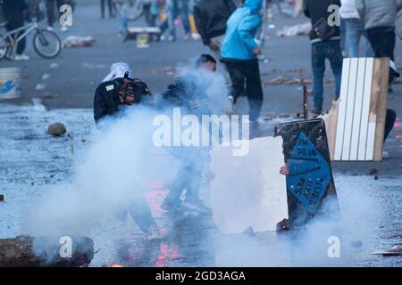 Bogota, Kolumbien, 09/08/2021, Demonstranten, die Holztüren aus Wasser- und Tränengaskanistern benutzten, die von einem gepanzerten Lastwagen der kolumbianischen Bereitschaftspolizei während der Anti-Regierung-Proteste angeschossen wurden, was in Zusammenstößen zwischen Demonstranten und der kolumbianischen Bereitschaftspolizei (ESMAD) endete, während die Demonstranten, die während der Anti-Regierungsproteste der letzten 3 Monate in den Tibabuyes lagerten, vertrieben wurden Im Norden Bogotas, Kolumbien Stockfoto