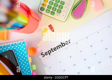 Zurück zur Schule. Blick von oben auf den weißen Schreibtisch mit Arbeitsbüchern, Schreibwaren und september-Kalender im Studentenzimmer an sonnigen Tagen. Stockfoto