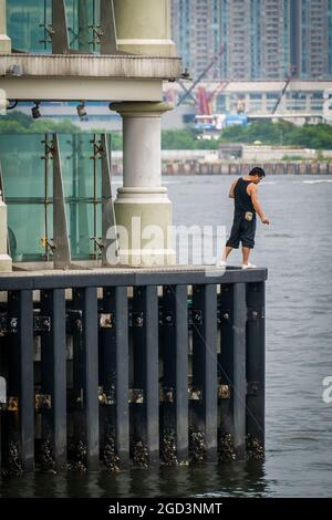 Ein Mann fischt vom Central Ferry Pier 8 auf Hong Kong Island Stockfoto