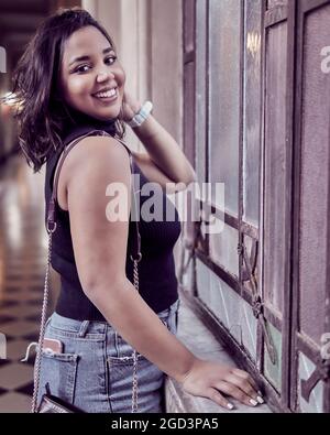 Porträt eines lächelnden Brünette Mädchen vor einem alten Vintage-Fenster. Argentinischer Lebensstil. Vertikal Stockfoto