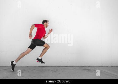 Fitness Running Mann Läufer Profil auf Wand weißen Hintergrund. Männlicher Sportathlet sprintet mit hiit High Intensity Intervall Training Workout Tragen Stockfoto