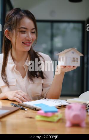 Ein Immobilienmakler demonstriert das Haus-Modell für Kunden, die sich für den Kauf einer Hausversicherung interessieren. Das Konzept der Hausversicherung und Immobilien. Stockfoto