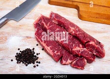 Rohes marmoriertes Rindfleisch mit Pfefferkorn auf Holzoberfläche Stockfoto