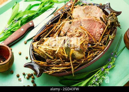 Köstliches Fleisch in frischem Heu gebraten. Gebackenes Schweinefleisch in würzigen Kräutern.Herbstfutter Stockfoto