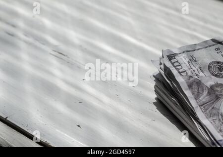 Eine Nahaufnahme eines Wades zerknitterten Geldes auf einem weißen Holztisch. Hundert US-Dollar. Stockfoto