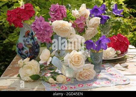 botanik, Rosen, Hortensien, platcodon grandiflorum in verschiedenen Vasen auf einem Tisch im Freien, ZUSÄTZLICHE-RIGHTS-CLEARANCE-INFO-NOT-AVAILABLE Stockfoto