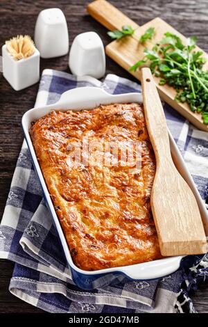 Herzhafte Kartoffel-kugel, gebackener Pudding oder Auflauf geriebener Kartoffeln in einer Auflaufform auf einem Holztisch, jüdisches Feiertagsrezept, vertikale Ansicht Stockfoto