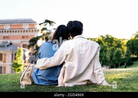 Unbekanntes junges Paar, das im Park sitzt und sich umarmt. Stockfoto