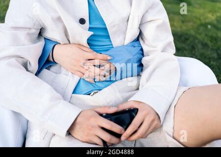 Unbekanntes, cooles Paar, das im Park sitzt und sich umarmt und den Abend genießt. Stockfoto