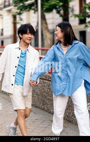 Glückliches asiatisches Paar, das an sonnigen Tagen in der Stadt herumläuft und die Hände hält. Stockfoto