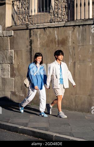 Glückliches asiatisches Paar, das an sonnigen Tagen in der Stadt spazieren und die Hände halten kann. Stockfoto