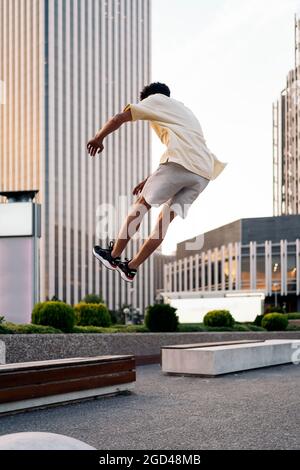 Cooler junger Mann, der Parkour-Tricks in der Stadt macht und Spaß hat. Stockfoto